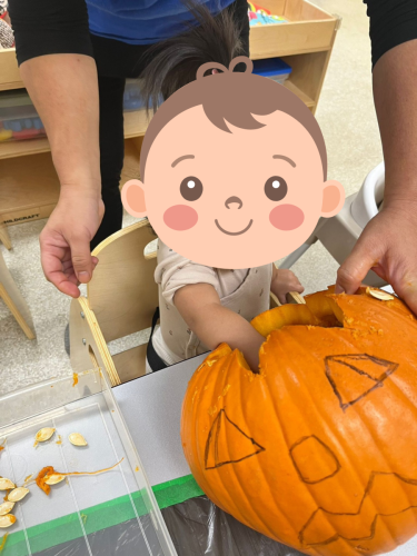 Infant exploring pumpkin seeds during Halloween activity at BKMCC Childcare in North Delta.