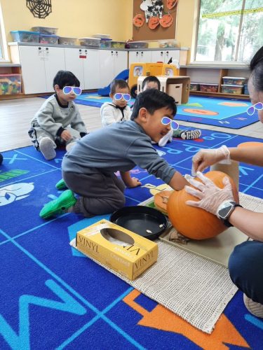 Preschool children exploring pumpkin seeds during Halloween activity at BKMCC Childcare North Delta.
