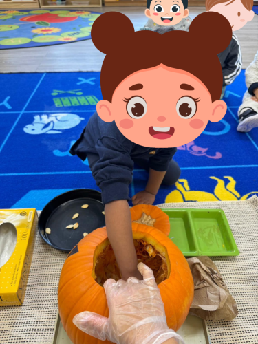 Toddler reaches into pumpkin during Halloween activity at BKMCC North Delta.